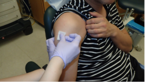 Use an alcohol prep pad (isopropyl alcohol 70% v/v) to disinfect the deltoid muscle injection site, located two finger widths below the acromion process.